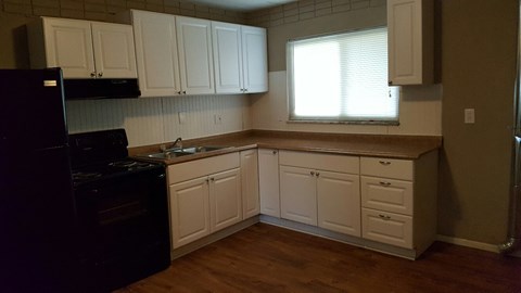 A kitchen with white cabinets and a black fridge.
