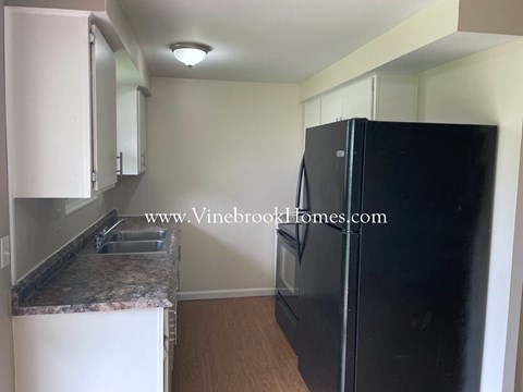 a kitchen with a black refrigerator and white cabinets
