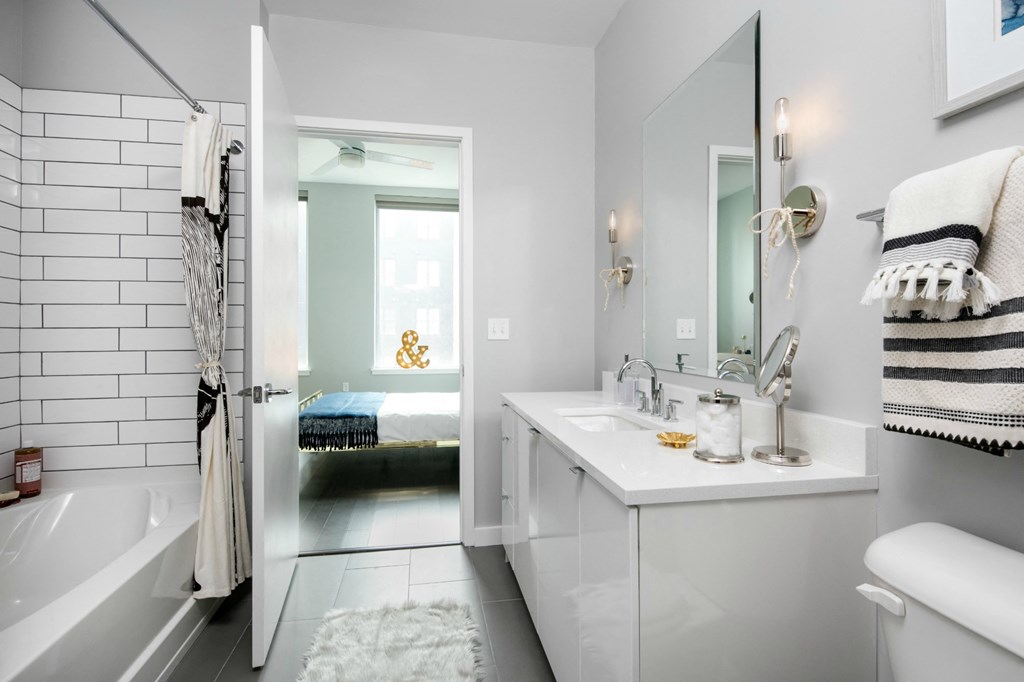 a white bathroom with a tub and a sink and a mirror