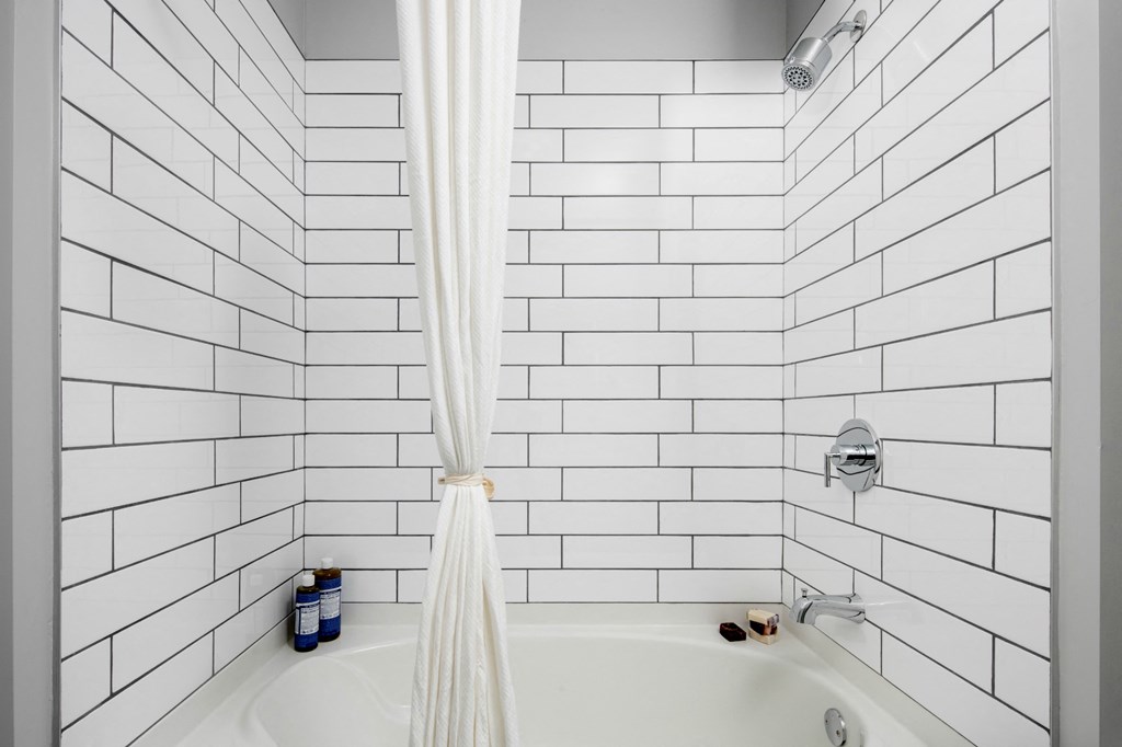 a white bathroom with white subway tile and a shower curtain