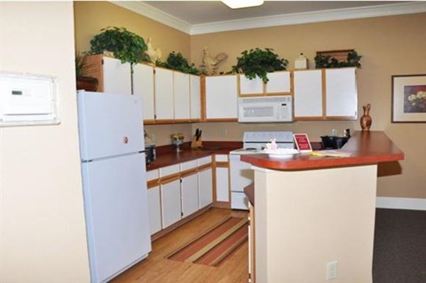 A kitchen with a white refrigerator and wooden floors.