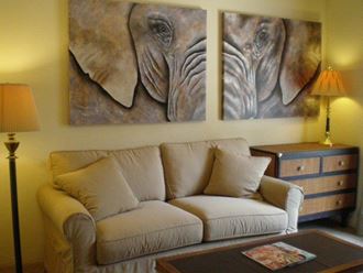 a living room with a couch and two paintings of an elephant