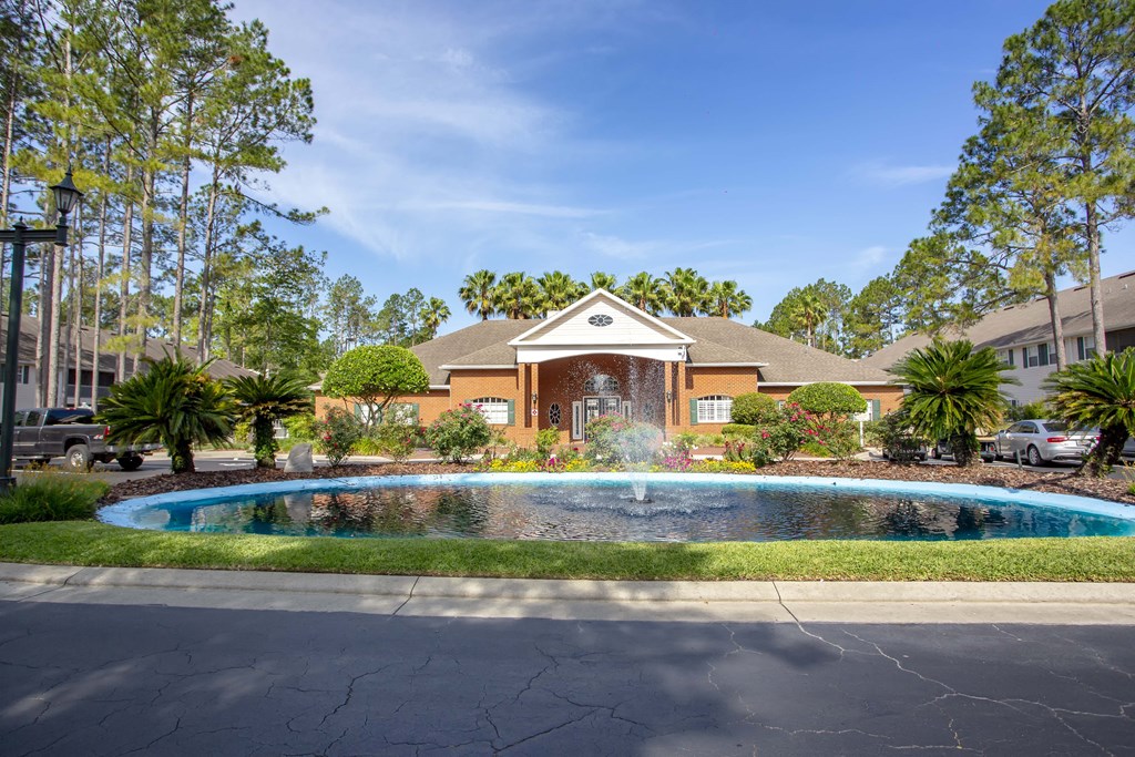 a pool in front of a house with a fountain