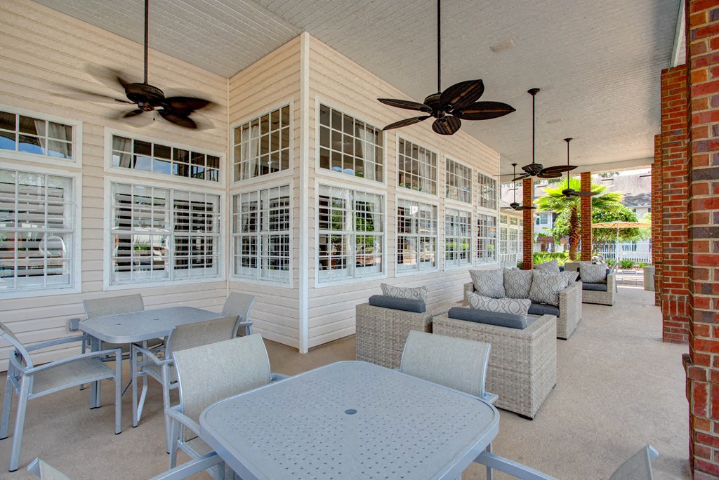 a covered porch with tables and chairs and windows