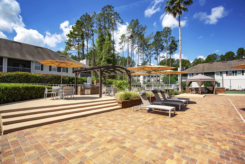 a patio with lounge chairs and umbrellas at the resort