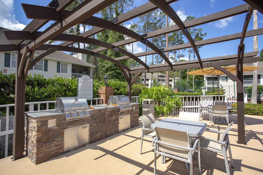 a patio with a grill and a table and chairs
