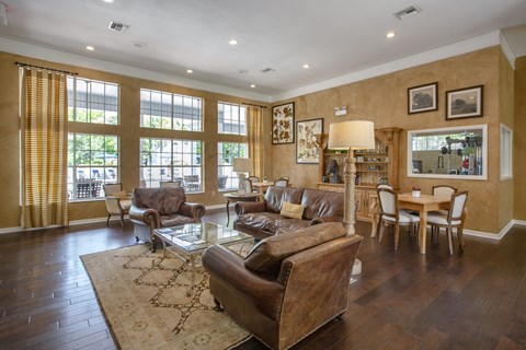 the living room has leather couches and a glass coffee table