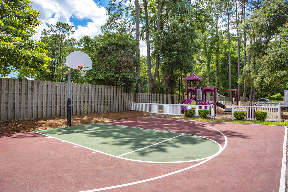 a basketball court in a backyard with a playground and playset