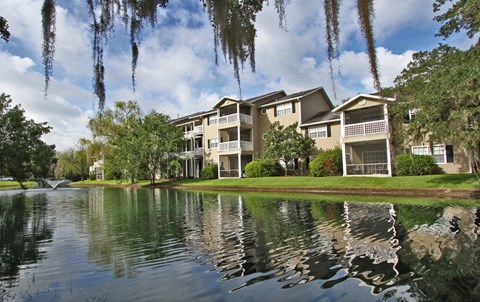 an apartment building overlooks a lake with moss covered trees
