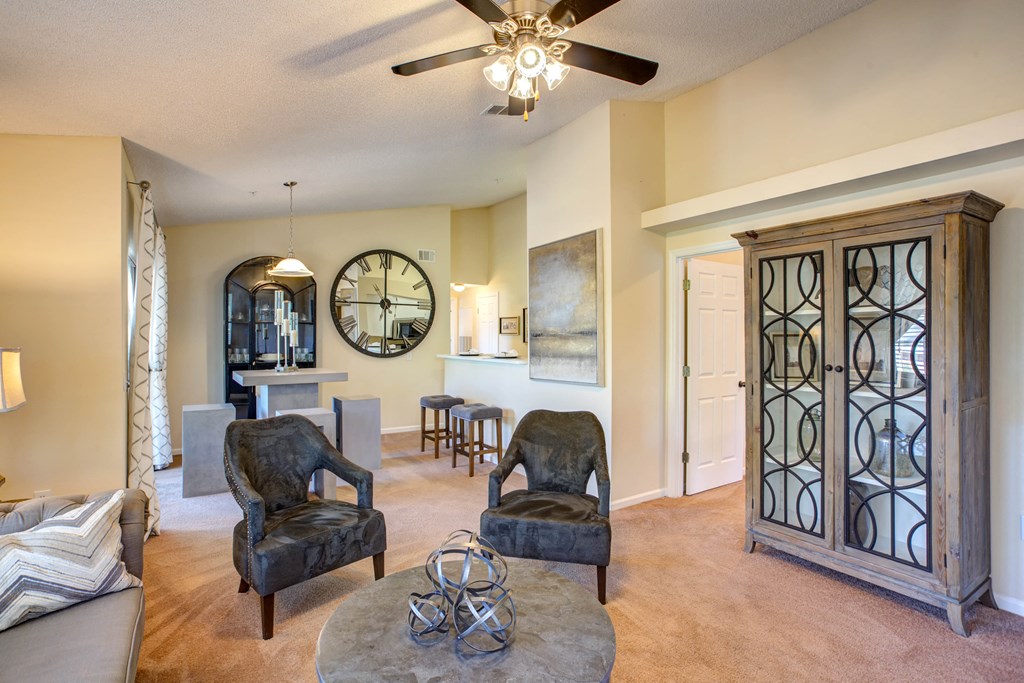 a living room with chairs and a ceiling fan