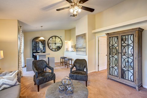 a living room with chairs and a ceiling fan