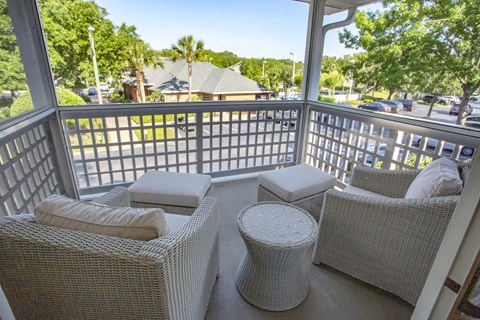 a porch with wicker chairs and a table on a balcony