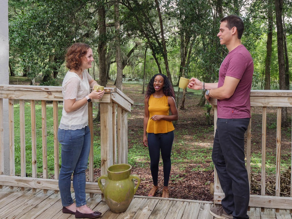 two women and a man standing on a deck talking
