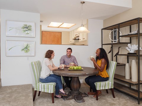 three people sitting around a table in a living room