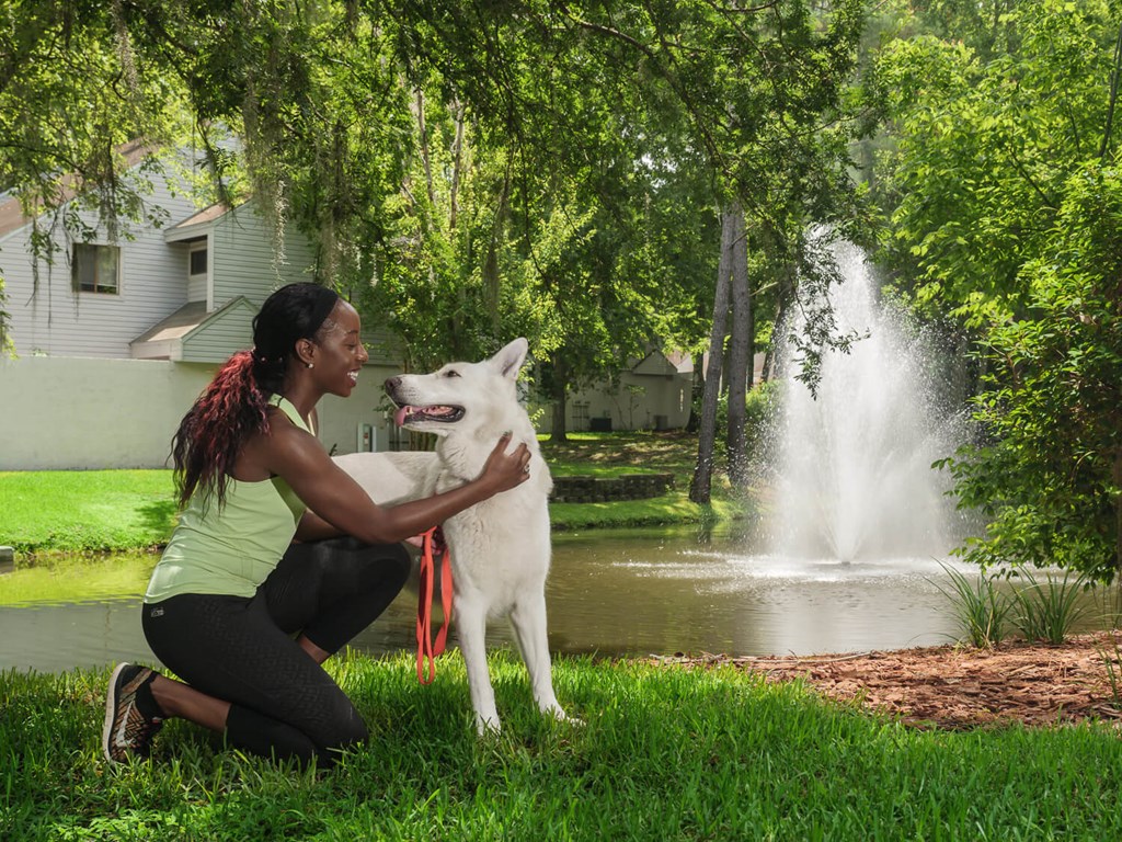 a woman is petting her dog in front of a fountain