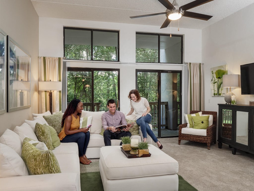 three people sitting on a white couch in a living room