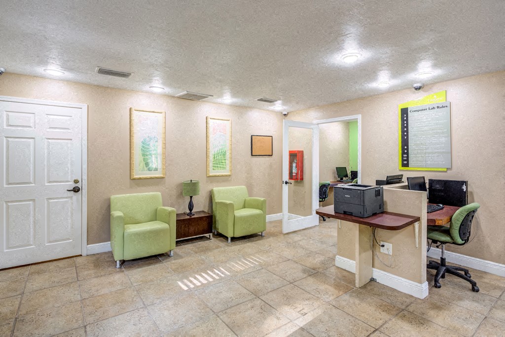a lobby with two chairs and a desk with a computer