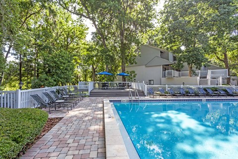 a swimming pool with chairs and a house in the background