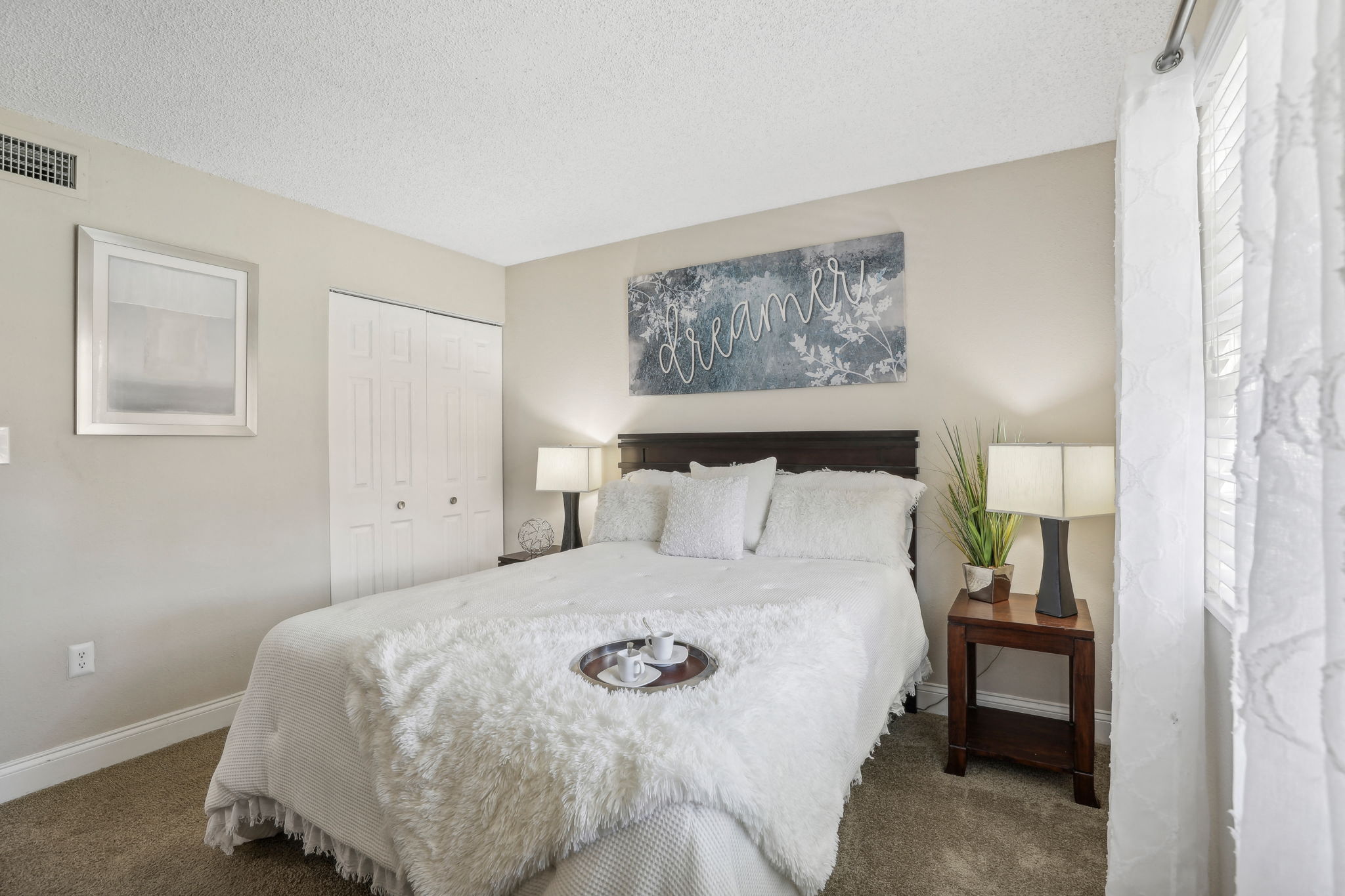 A bedroom with a large bed and a painting on the wall.