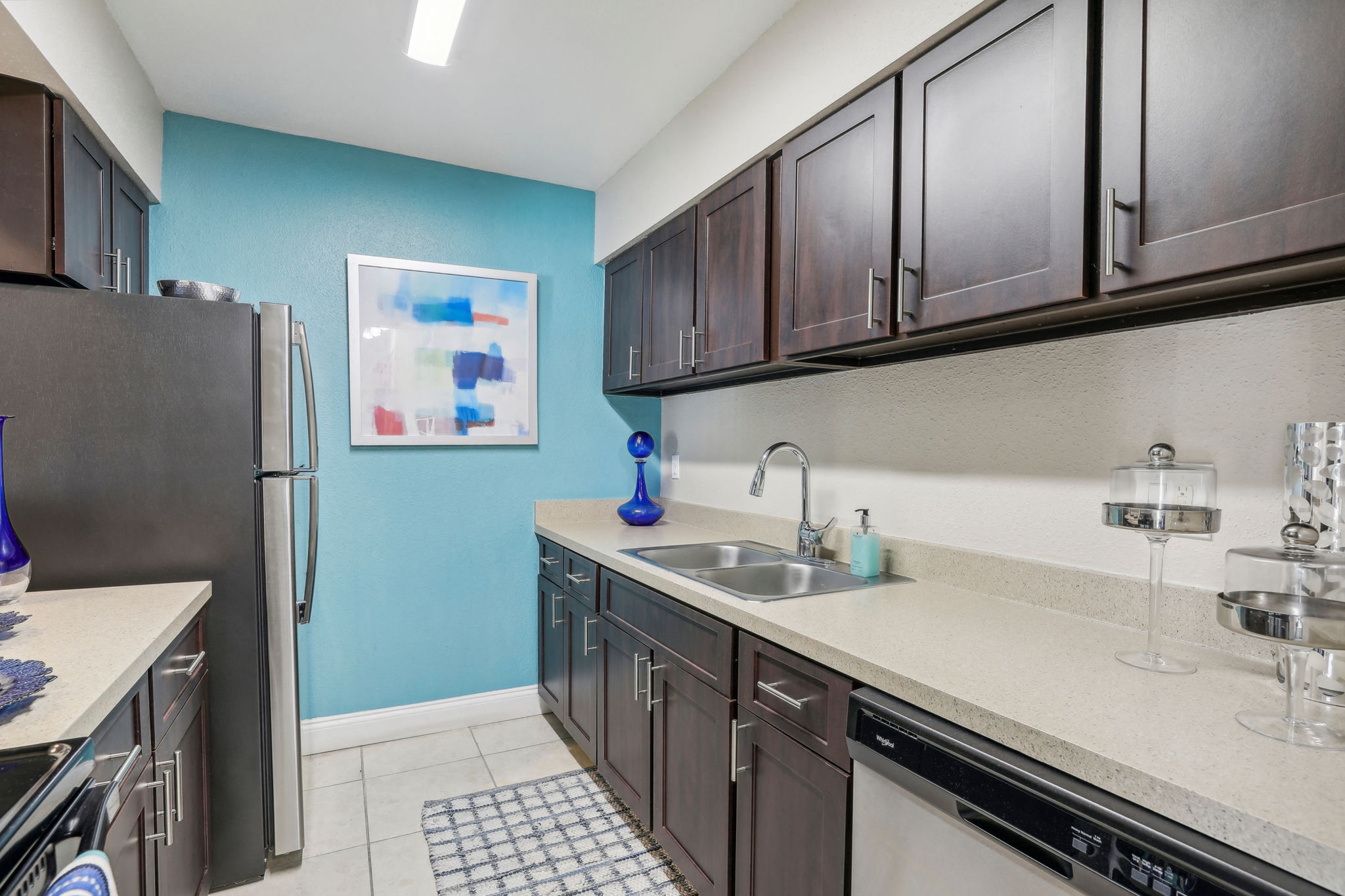 A kitchen with a black refrigerator and brown cabinets.