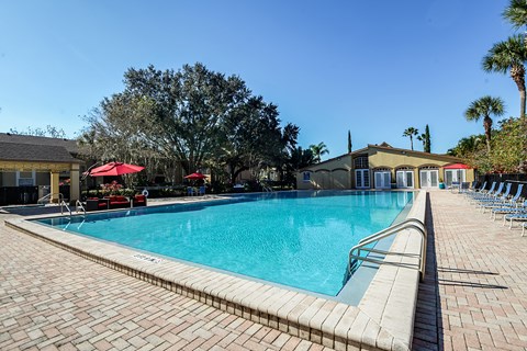 A large swimming pool surrounded by a brick patio.