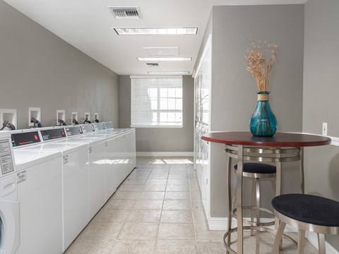 A laundry room with a row of washers and dryers.