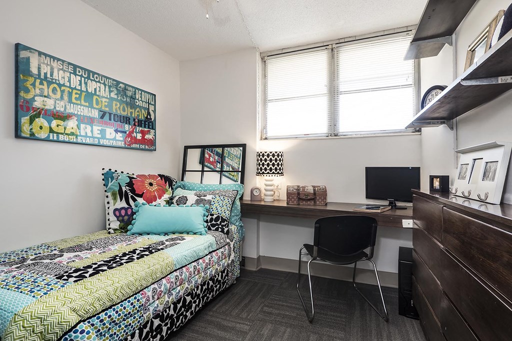 a bedroom with a bed and a desk with a computer