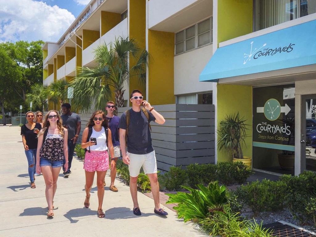 a group of people walking down a sidewalk in front of a building