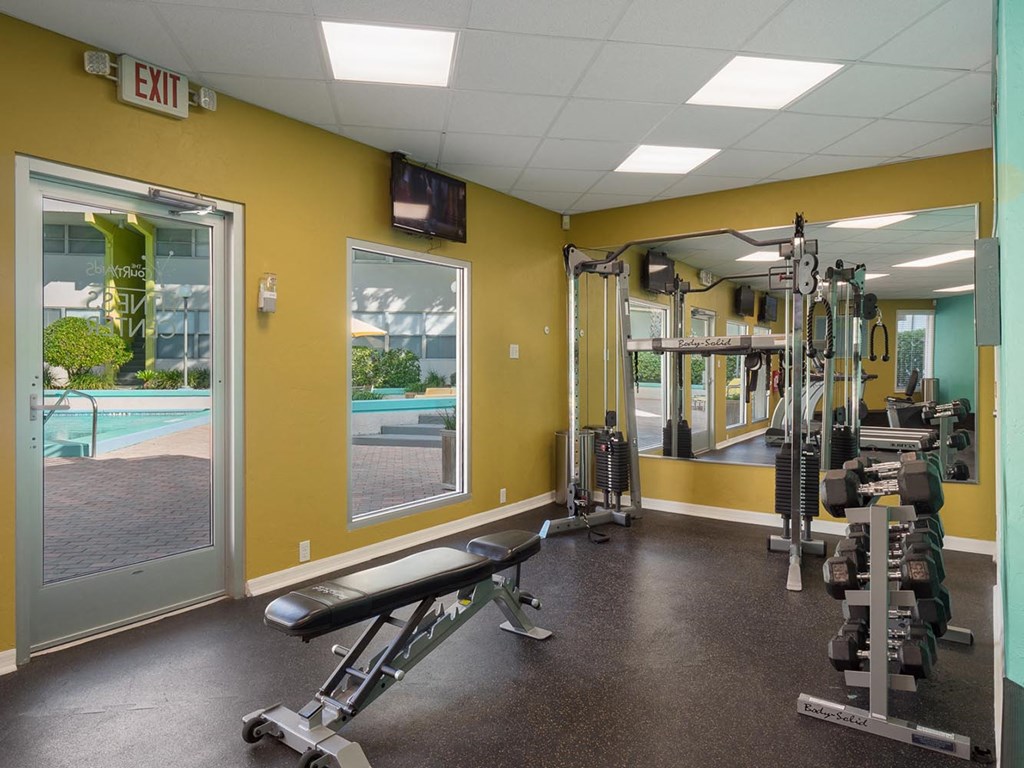 a gym with weights and mirrors and a pool