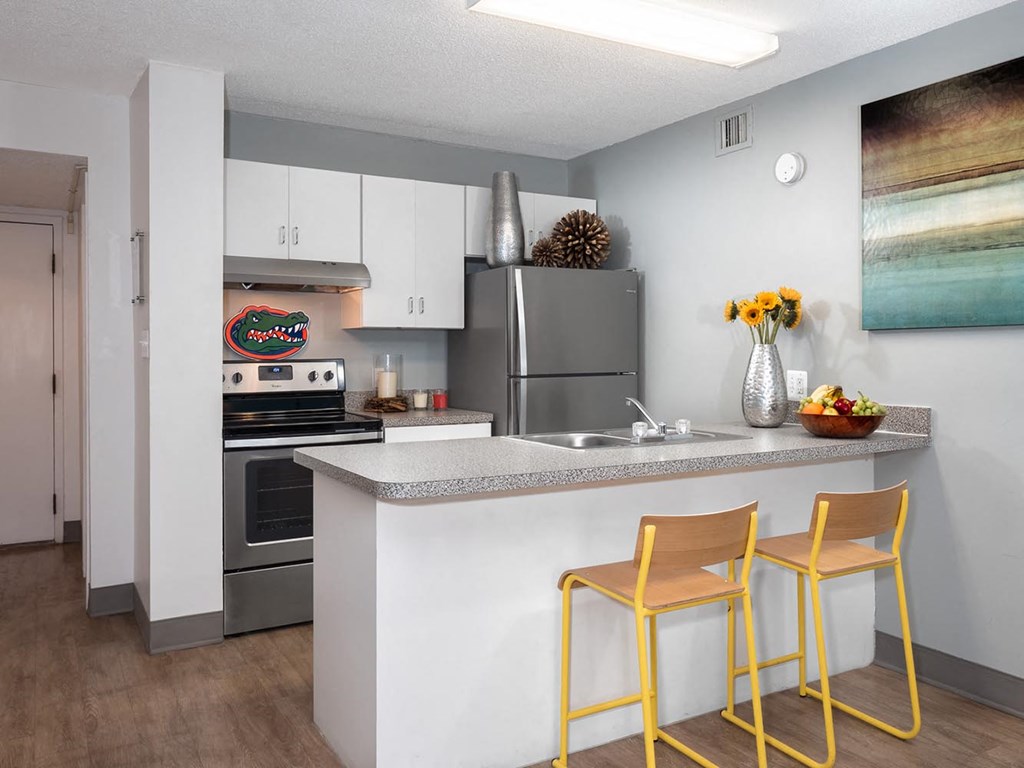 a kitchen with stainless steel appliances and a counter with two yellow chairs