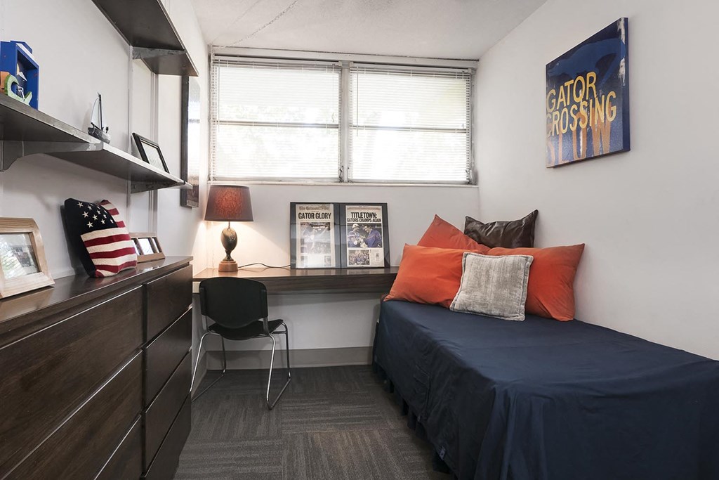 a bedroom in a residence hall with a bed and a desk