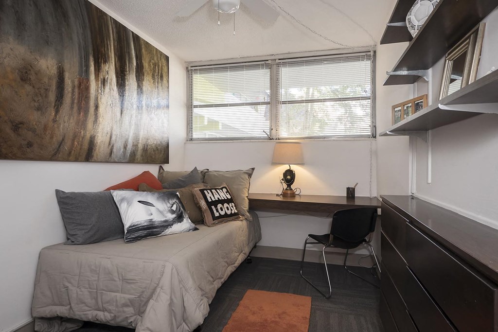 a bedroom with a bed and a desk and a window