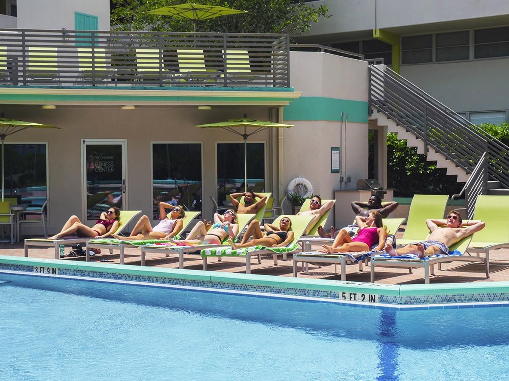 a group of people laying in lawn chairs by a swimming pool