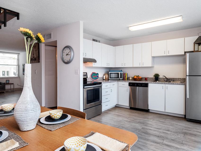 a kitchen with white cabinets and stainless steel appliances and a dining table