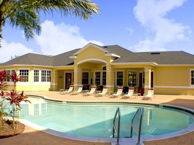 a swimming pool with chairs in front of a house