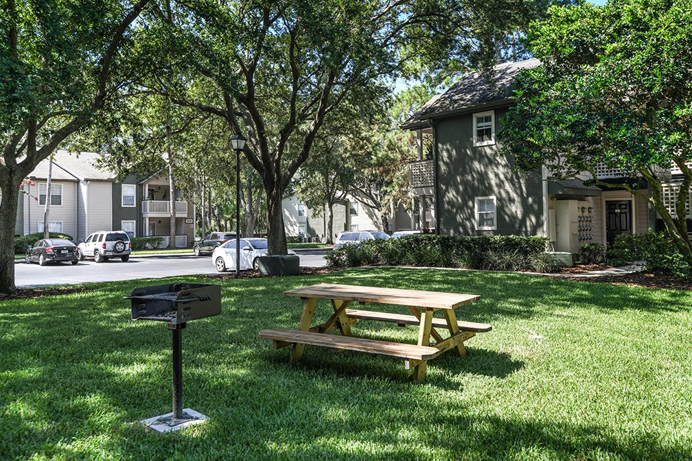 a picnic table in a yard next to a grill