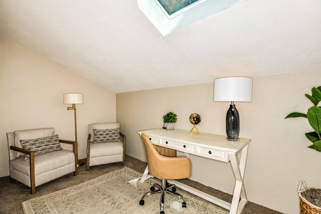 a home office with a desk and chairs and a window