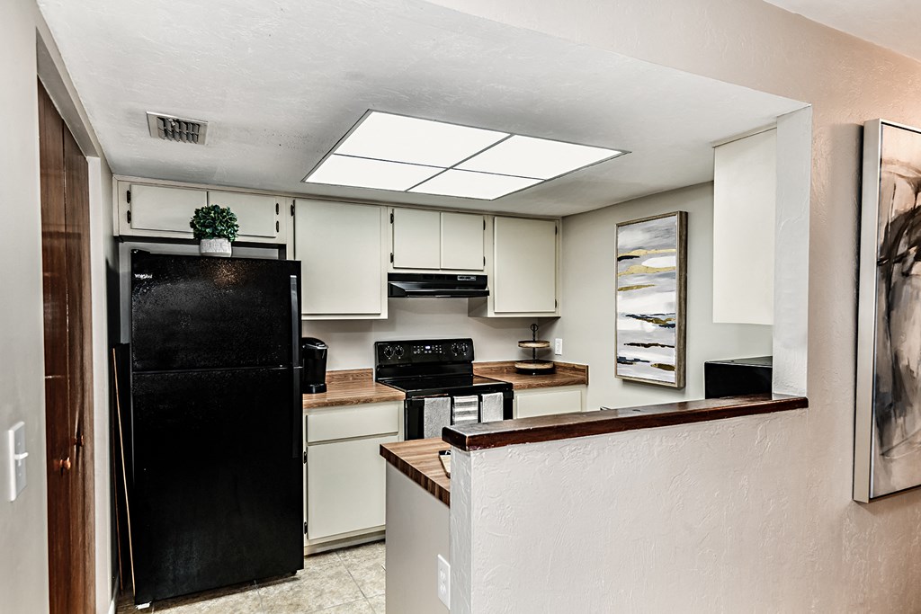 a kitchen with white cabinets and a black refrigerator