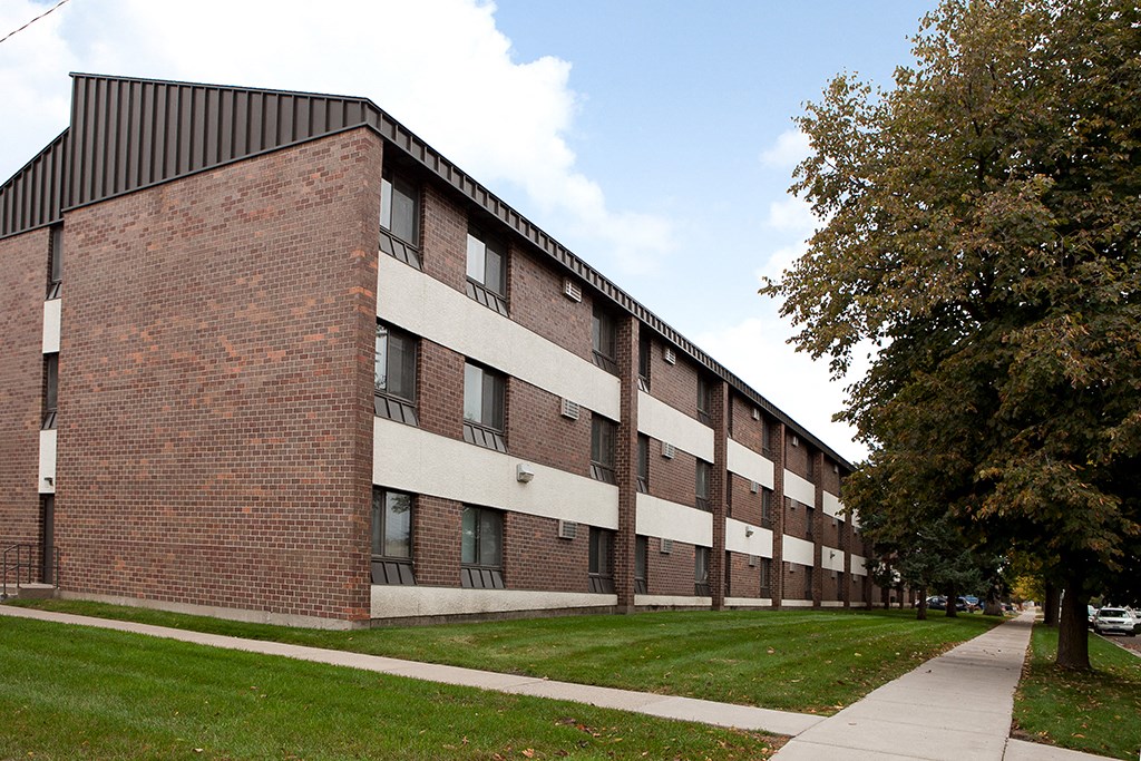 the side of a brick building with grass and trees