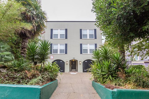 A grey building with a green border around the plants.
