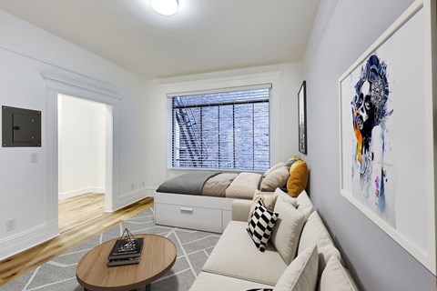 A living room with a couch, a coffee table, and a painting on the wall.