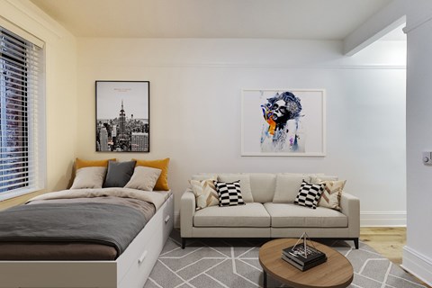 A bedroom with a bed, couch, and a painting on the wall.