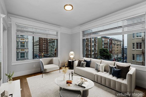 A living room with a couch, a coffee table, and a large window with blinds.