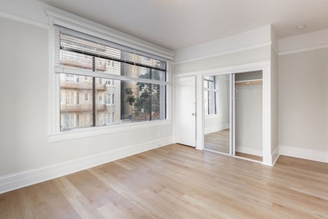 A room with a large window and wooden flooring.