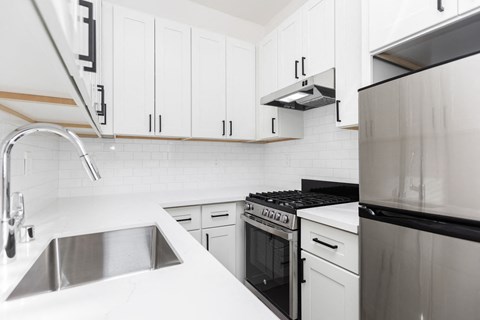 A modern kitchen with white cabinets and stainless steel appliances.