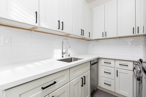 A kitchen with white cabinets and a white countertop.