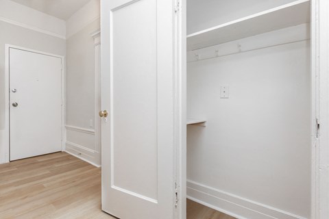 A white door is open to a room with a white wall and a light switch.