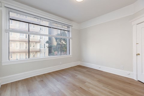 A room with a large window and wooden flooring.
