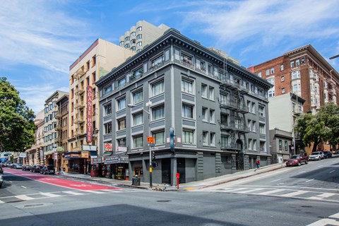 A street view of a city with a grey building in the middle.