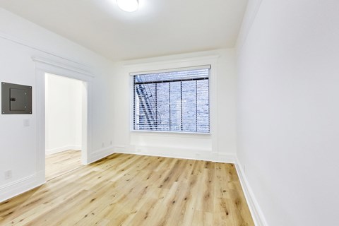 A room with wooden floors and a window with blinds.
